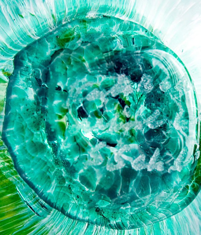 Mottled teal green glass was blown into an optic mold (vertical optic panel decor) and hand finished with an applied yellow and orange speckled stem. It is blown hollow. The mottling is raised a bit giving the fruit's skin a slight texture.