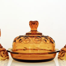 Set of depression glass candlestick holders and covered dish in golden amber.