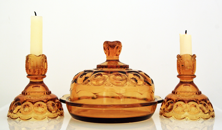 Set of depression glass candlestick holders and covered dish in golden amber.