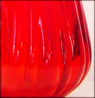 Red glass hand blown into mold then hand stretched, swung and tooled.