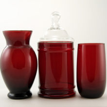 In Anchor Hocking's patented Royal Ruby glass color. Set includes: (1) covered canister just the right size for vanity items; (1) a vase for your posies; and (1) matching tumbler