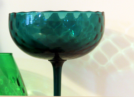 The stem is applied to the base and the bowl. The bowl features pillow optic decor. There is Circus tent fringe on the rim. The pontil is half moon shaped.
