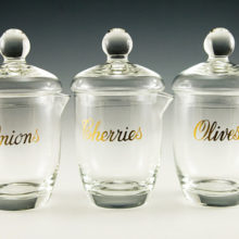 Set of three blown glass bar condiment jars for cherries, onions and olives. The jars are individually labeled with cursive font in real gold paint.