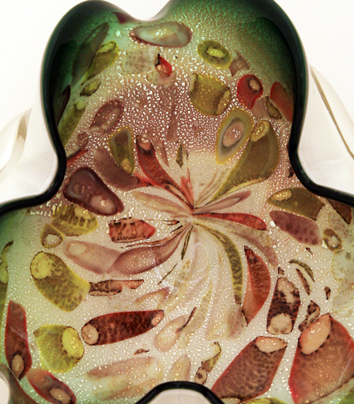 This awesome, quality glass was hand-blown and hand-folded. Triple cased. Dark green, internally decorated with earth-tone bits of colored canes and silver flecks, encased in opaque milk glass, and finished with a layer of crystal.