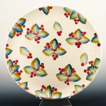 This hand-made italian redware majolica serving platter is decorated with leaves and berries in blue, green and red on creamy white background.