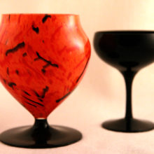 The glass footed vase is hand blown with orange decorated inner casing and clear outer casing.