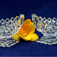 A pair of oval solid pedestal crystal salt cellar with diamond shaped base, sawtooth rim and overall diamond pattern on sides and bottom of base.