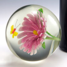 Trapped inside the large solid glass ball is a yellow butterfly and pink flower made of glass.