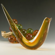 Made in cased glass using amber stained glass and a layer of clear glass and then hand-working the glass into the object shape. The clear glass eyes and beak are applied.
