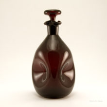 This Blenko glass pinch decanter is in excellent condition. A full ring of bottom-wear caused by years of surface contact is on the base. The glass is brilliant. The color is uncommon.  It is a very dark red, with slight hints of deep amethyst.