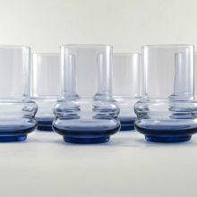 Blown glass hoop tumbler set of 6 made of high quality glass with weighted bases. Hooped glass was popular in the Art Deco era through the Mid-20th Century. We are unsure of the maker, but lean towards Scandinavian origin.  Tiffin Glass (USA) made Swedish styled glass much like this too. The color matches Tiffin's Copen Blue, a light smoky blue.