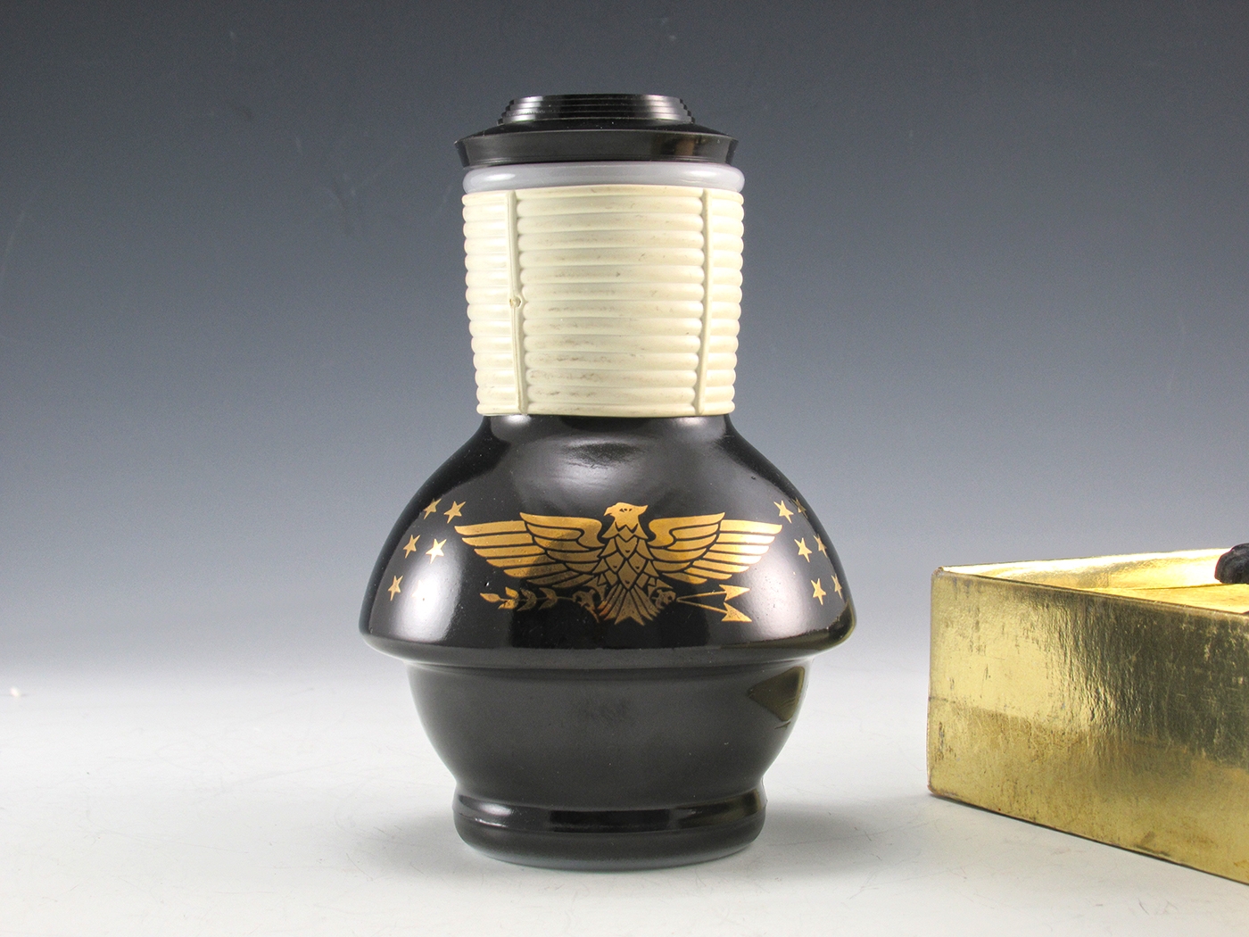 The Glasbake Hottel appears unused. Made of white opaque glass enameled in black. The gold eagle is in excellent condition, all gold present. Black areas in the images are caused by reflections.