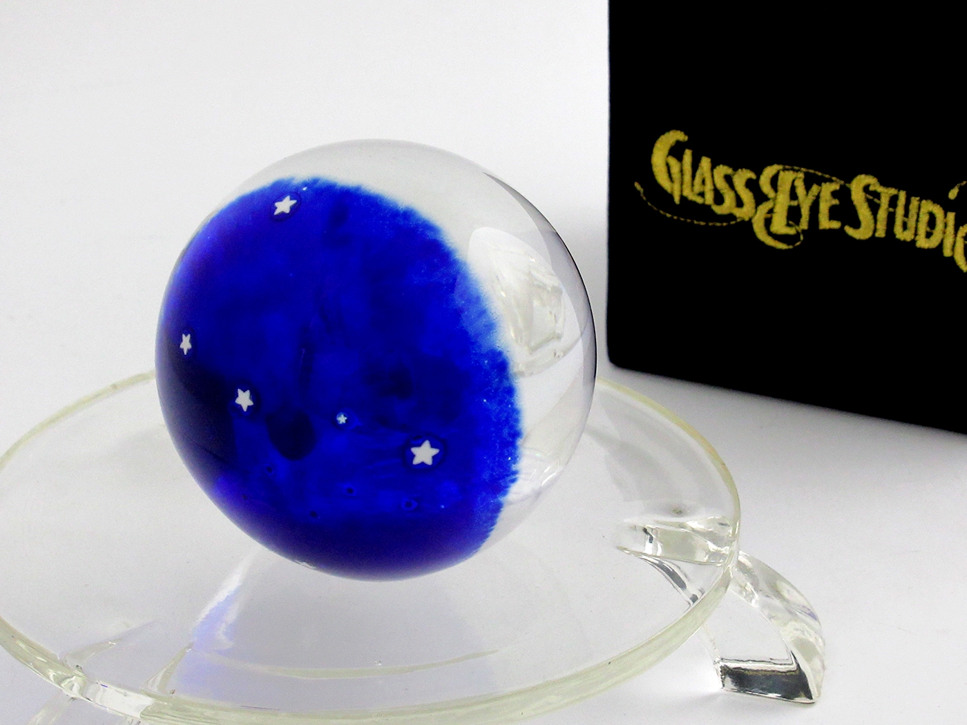 The back of the Glass Eye Studio Earth Rising paperweight is externally adorned with stars which can be seen when peering through the paperweight towards the earth.
