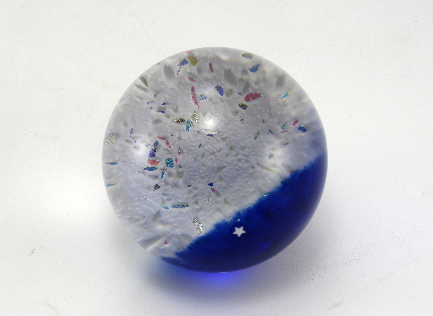 The lunar surface inside the paperweight is made of white inclusions with small reflective bits of color (see image). It is generally assumed the moon is white and gray. The moon has colors! Actual color enhanced images show shades of different colors caused by metals and minerals and lots of light emitting areas.