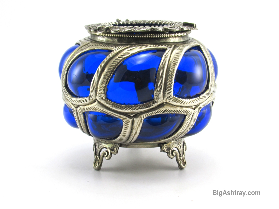 Antique Cobalt blue caged glass ashtray bowl. The artist blew the glass parison directly into the hand-formed metal cage coating the interior in a thick layer of rich cobalt blue glass and causing it to bulge out of the metal openings. This exceptional decor method is a revival of Roman era glass, copied from excavated examples discovered in the 17th Century.